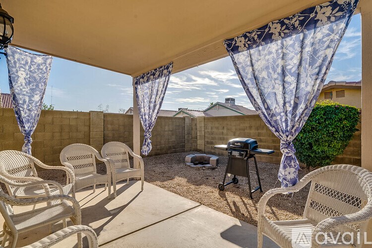 A patio with white chairs and blue curtains.
