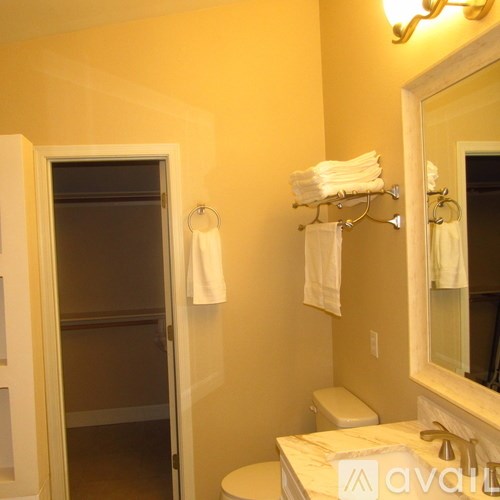 A bathroom with a toilet, a mirror, and towels.