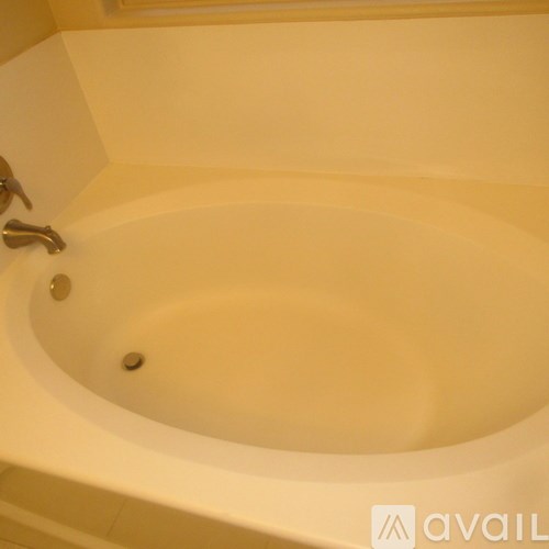 A white bathtub with a silver faucet and a drain.