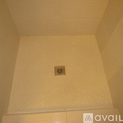 A shower with a drain in the middle of the floor.