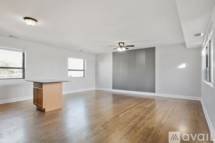 A spacious room with wooden flooring and a ceiling fan.