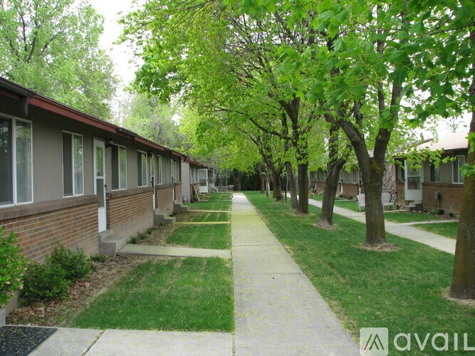 A tree-lined walkway separates apartment buildings.