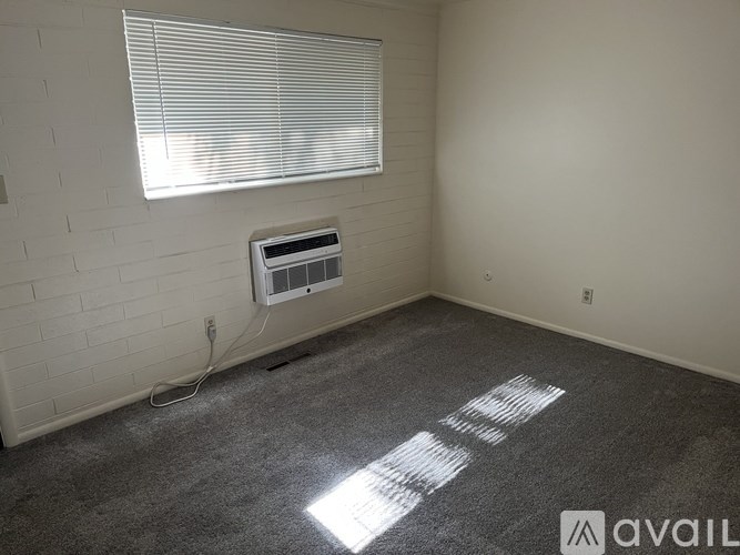 A room with a window covered by blinds and a white electrical outlet on the wall.