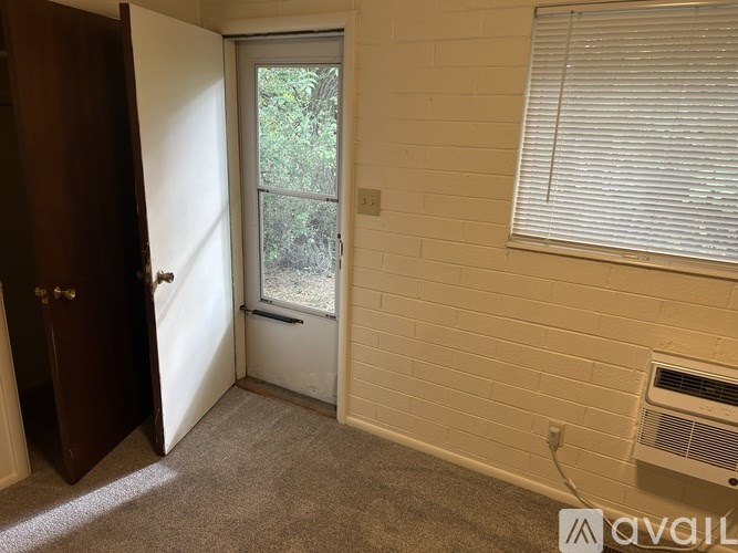 A room with a window, a door, and a wall heater.