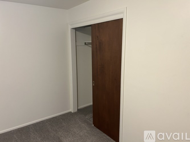 A room with a white wall and a brown door.