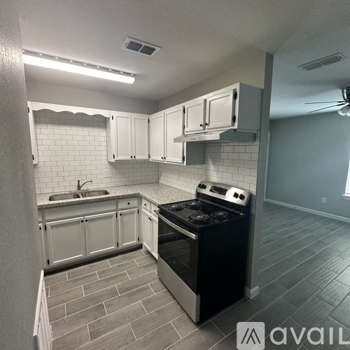 A kitchen with a black stove top oven and white cabinets.
