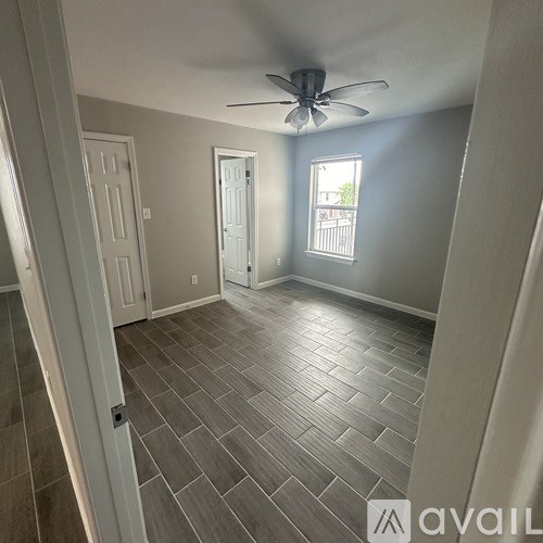 A room with a ceiling fan and a window with a view of a balcony.