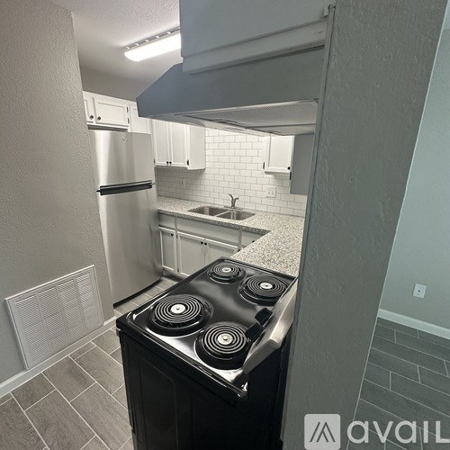 A kitchen with a black stove top oven and white cabinets.