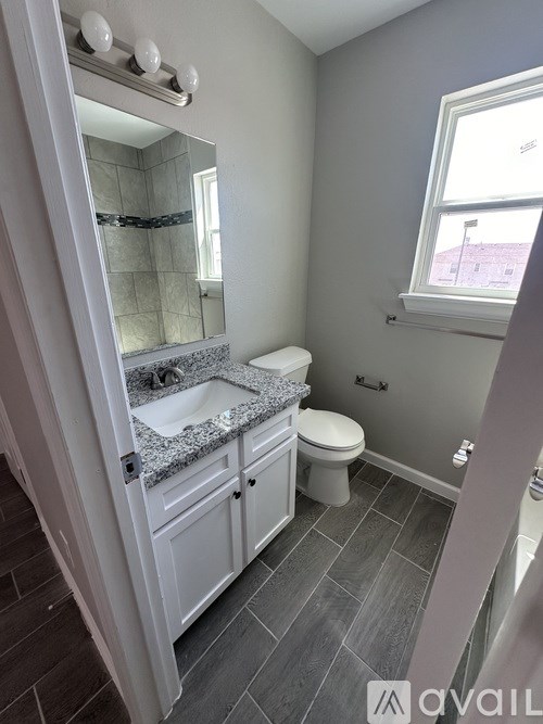A bathroom with a toilet, sink, and mirror.