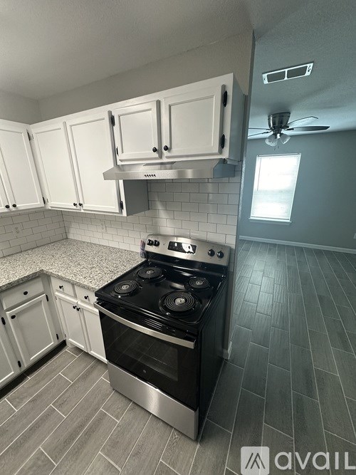 A kitchen with a stove top oven and white cabinets.