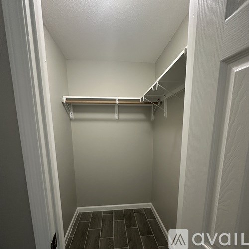 A small, empty walk-in closet with a white door and a white shelf.