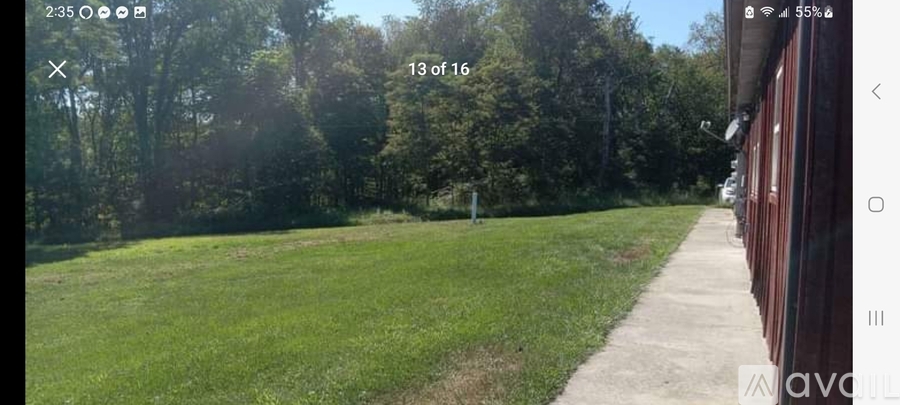 A grassy field with a walking path and trees in the background.