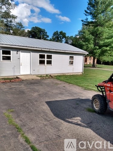 A silver building with a red vehicle in front of it.