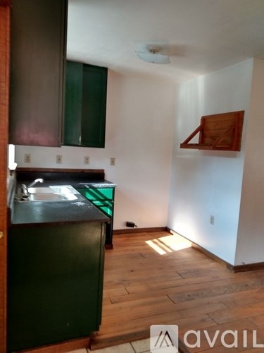 A kitchen with a green fridge and wooden floors.