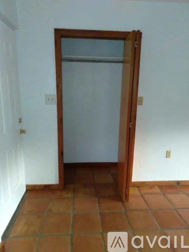 A white door with a gold handle is open to a backyard.