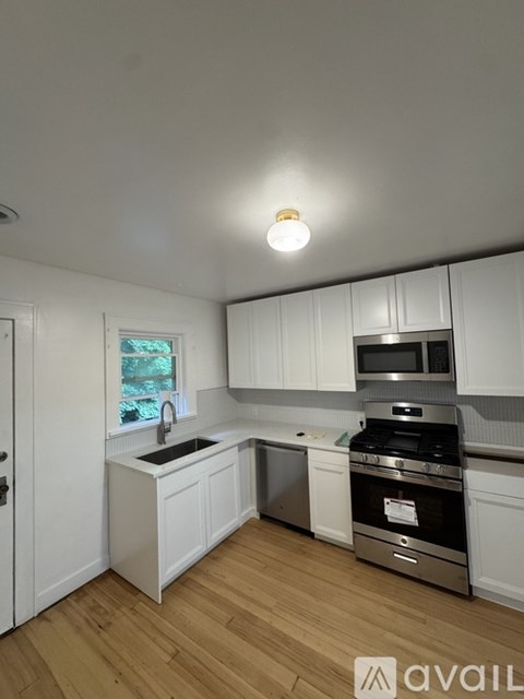 A kitchen with white cabinets and a wooden floor.