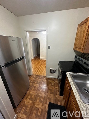 A kitchen with a stainless steel refrigerator and wooden cabinets.