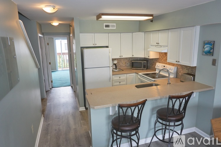 A kitchen with a refrigerator, microwave, oven, and washing machine.