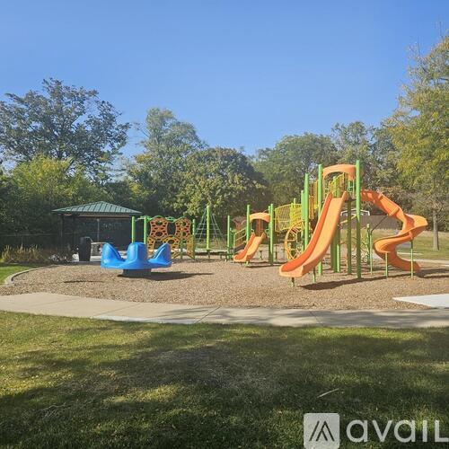 A playground with a green roofed structure, a blue slide, and an orange slide.