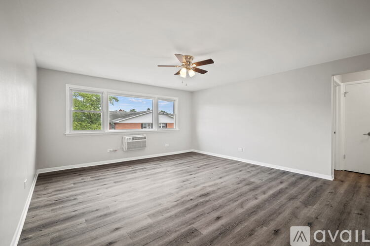 A room with a ceiling fan and a window overlooking a building.
