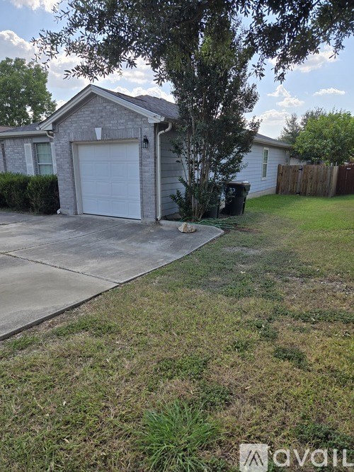 A house with a white garage door and a tree in front.