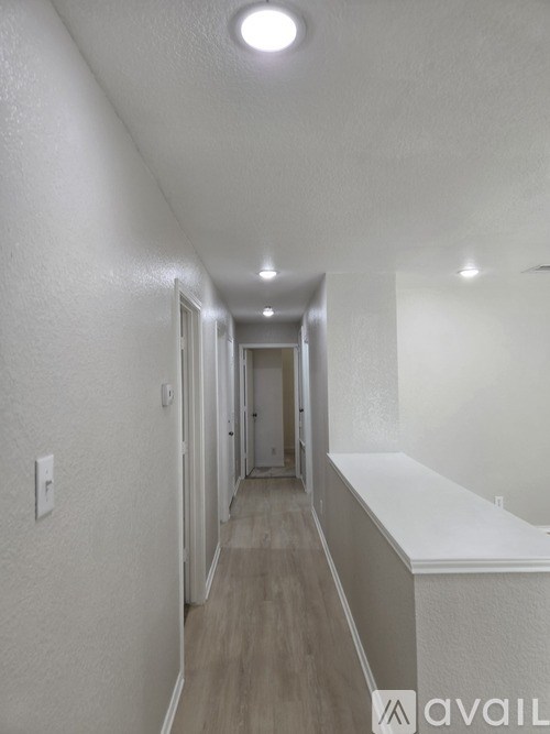 A long hallway with white walls and wood flooring.