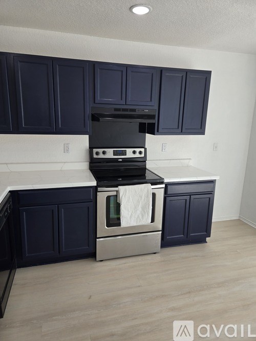 A kitchen with dark blue cabinets and a stainless steel oven.
