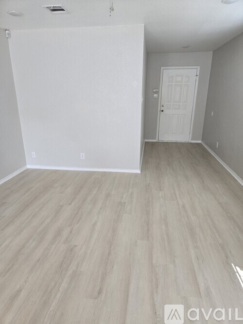 A room with a white door and wooden flooring.