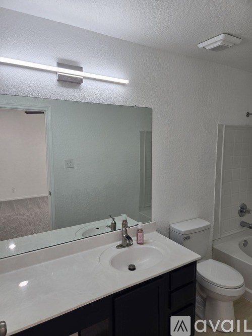 A bathroom with a sink, toilet, and mirror.