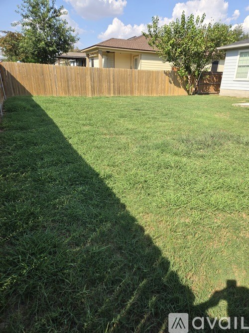 A backyard with a wooden fence and a house in the background.