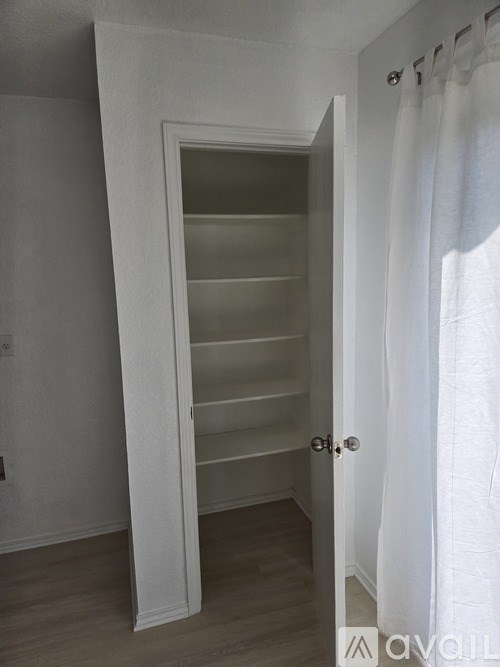 A white door with a glass panel is open to a hallway.