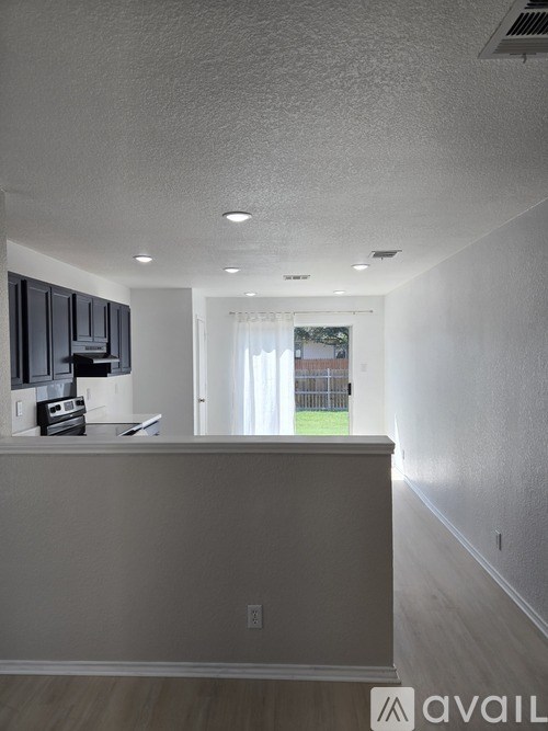 A well-lit room with a kitchen area and a view of a backyard.