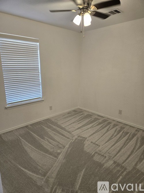 A room with a carpeted floor and a ceiling fan.