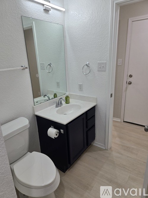 A bathroom with a toilet, sink, and mirror.