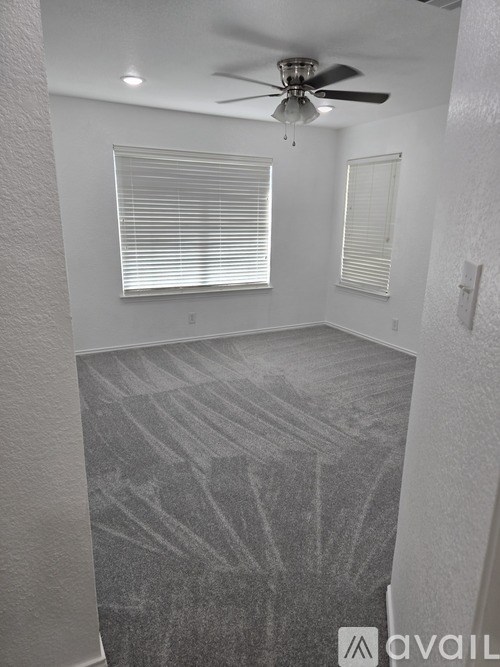 A room with a ceiling fan and a window with blinds.