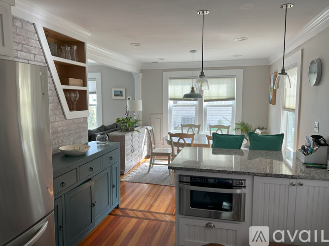 A kitchen with a refrigerator, oven, and a dining table with chairs.