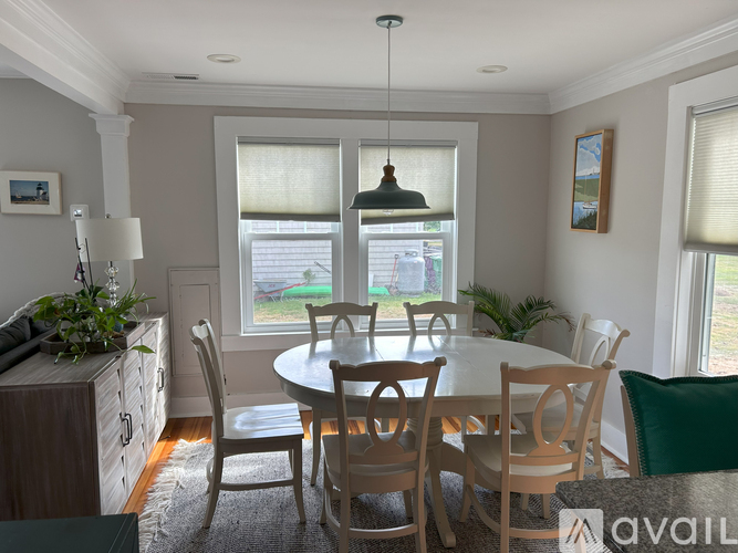 A dining room with a white table and chairs.