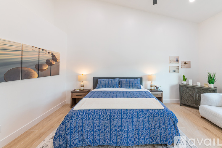 A bedroom with a large bed and a painting on the wall.