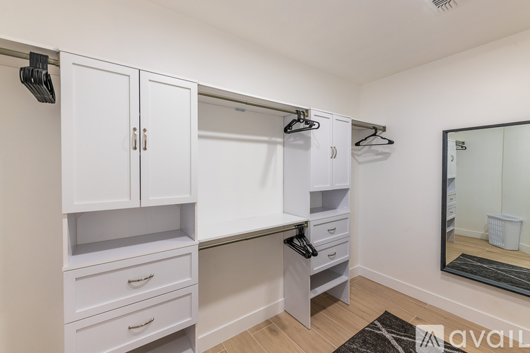 A spacious walk-in closet with white cabinets and drawers.