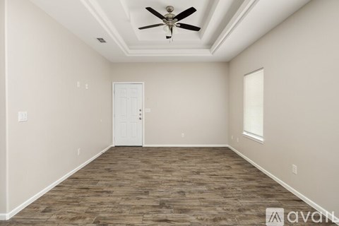 A room with a ceiling fan and wooden flooring.
