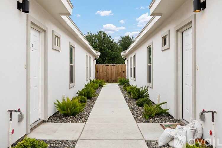 A white house with a long walkway and a wooden fence.