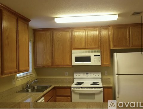 A kitchen with wooden cabinets and a white stove top oven.