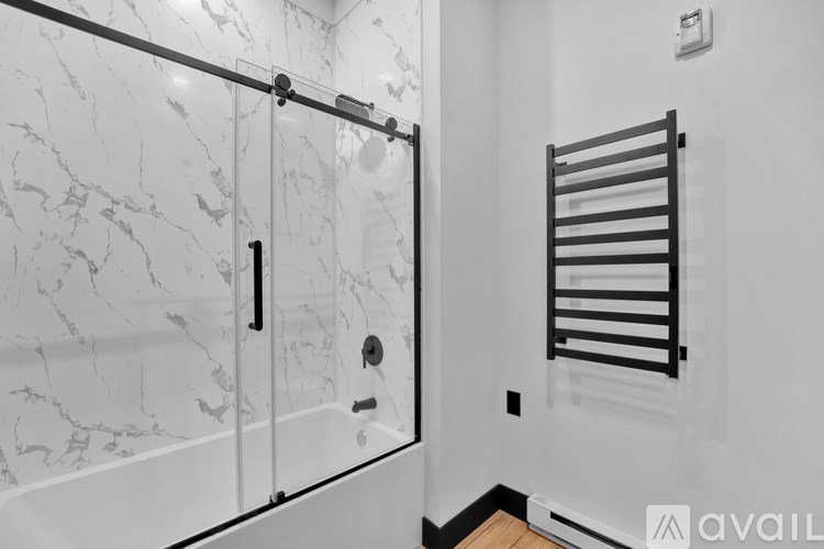 A bathroom with a marble wall and a glass shower stall.