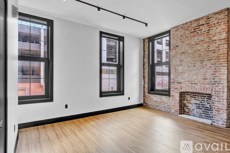 A room with a brick fireplace and wooden floors.