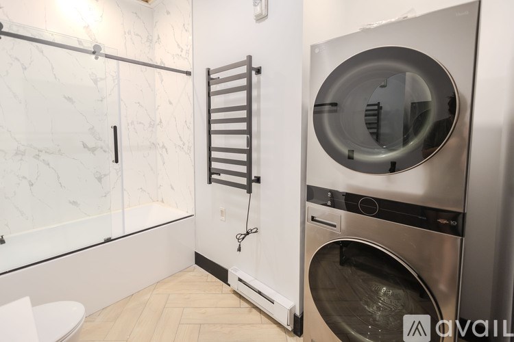 A modern bathroom with a walk-in shower and a washer and dryer.