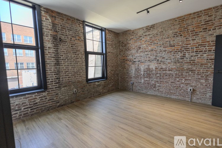 A room with wooden floors and a brick wall.