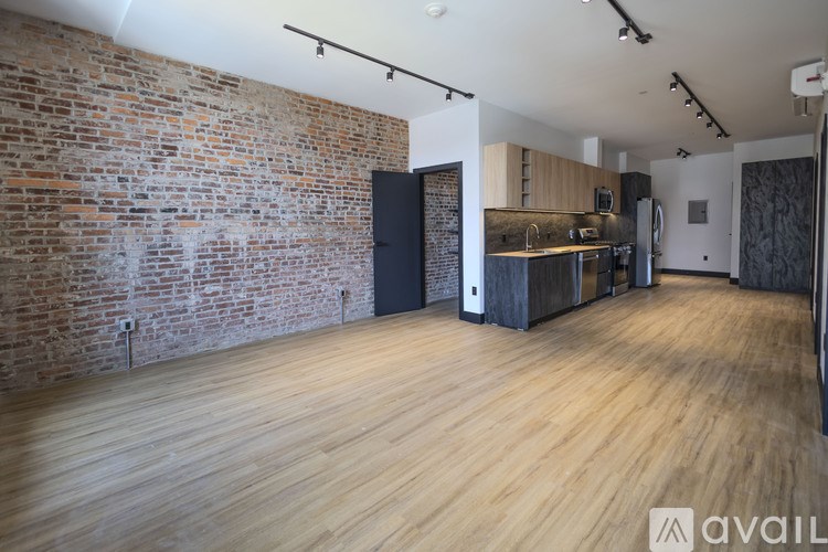 A room with wooden floors and a brick wall.