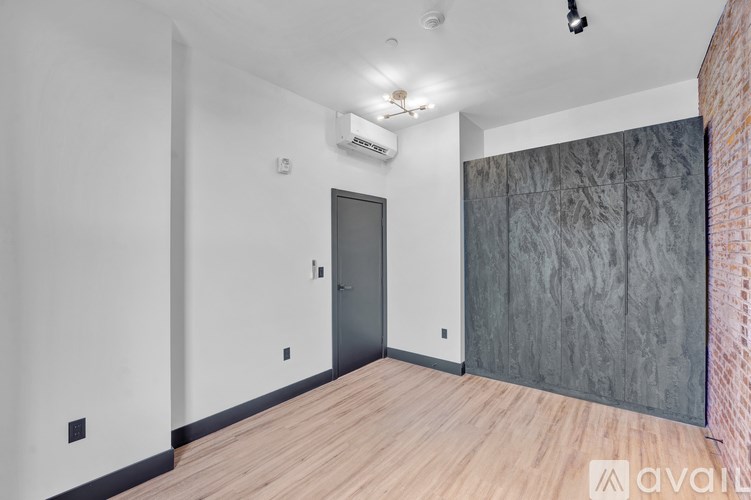 A room with a grey door and a brick wall on the side.