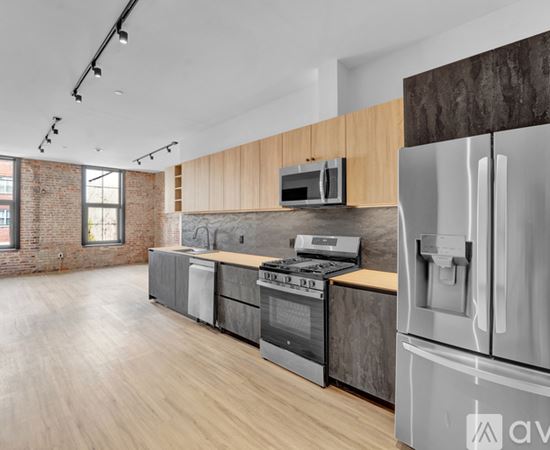 A modern kitchen with stainless steel appliances and wooden floors.