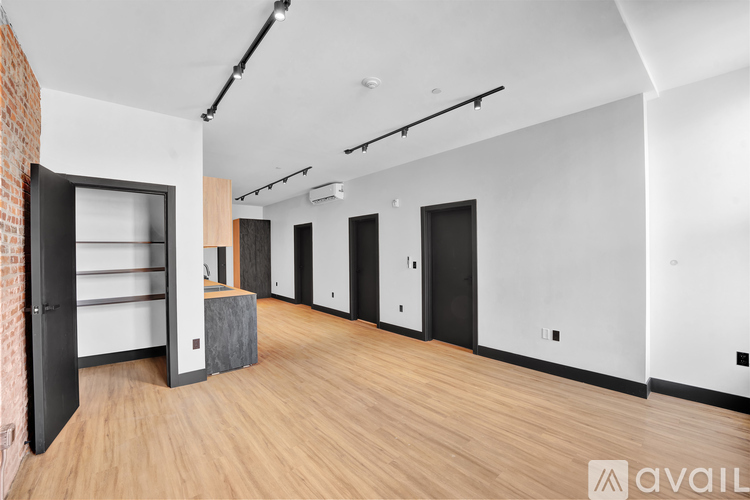 A room with a brick wall and wooden floors has a large open door.